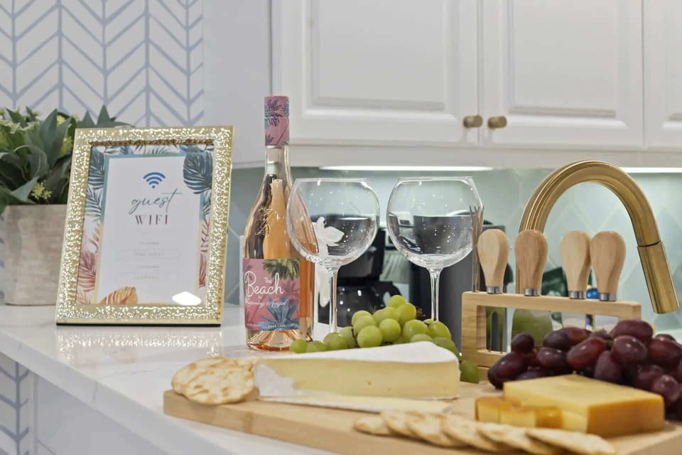 A modern kitchen counter set with wine, cheese, grapes, and a guest wifi sign for a welcoming experience.