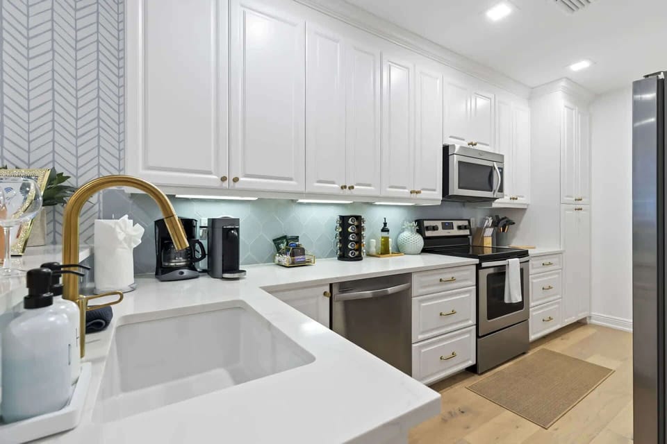 Modern kitchen with white cabinetry, brass fixtures, and stainless steel appliances.