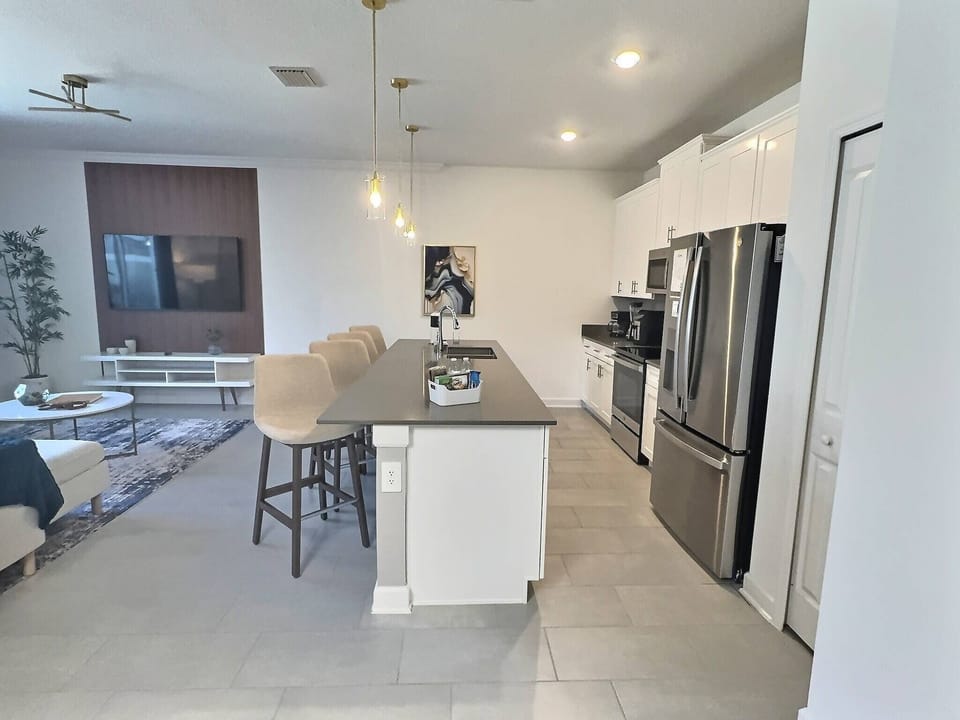 This bright kitchen boasts stainless steel appliances and a spacious island with stylish bar stools, ideal for casual dining. Warm wood accents and soft lighting set a welcoming atmosphere for every meal.