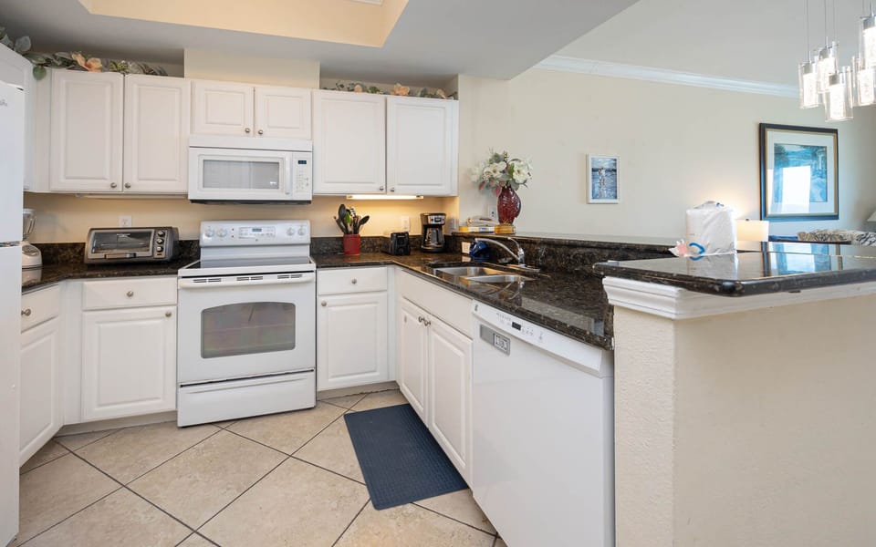 This kitchen features sleek white cabinetry, granite countertops, and essential appliances, perfect for preparing meals