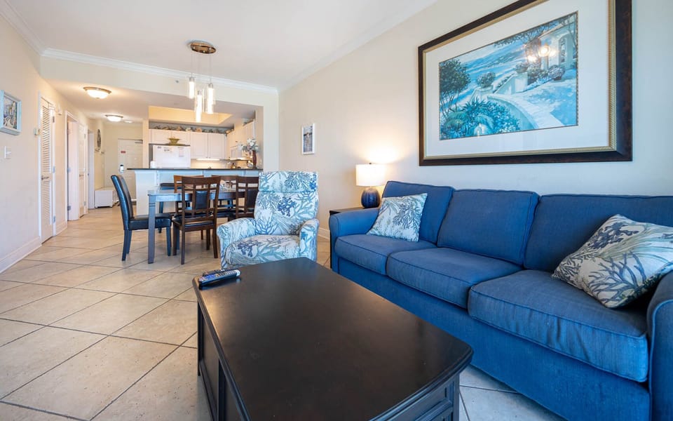 The living area features a cozy blue sofa, a stylish chair, and a dining table, perfect for relaxing and enjoying meals