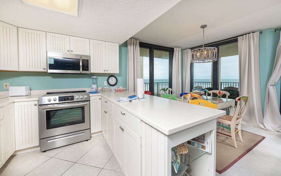 Cheerful dining chairs brighten your space as coastal views stretch beyond your sliding doors in the kitchen area