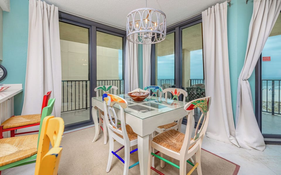 Colorful chairs surround the glass dining table as you enjoy beach views from the dining area