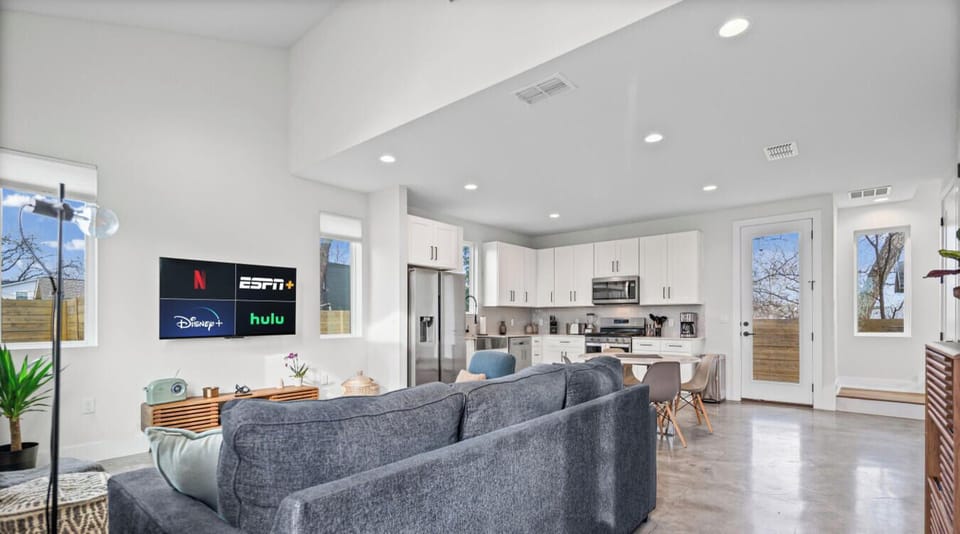 Open-concept living with a comfy couch, big smart TV, and a bright, fully stocked kitchen for easy nights in.