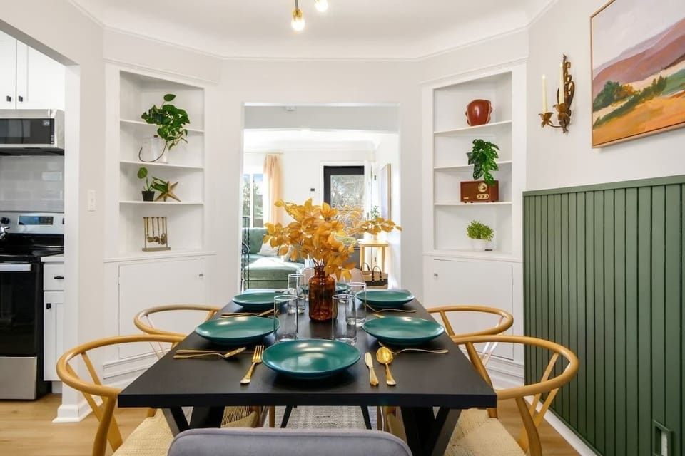 Dining area w/ round table, natural textures & stylish green accent wall