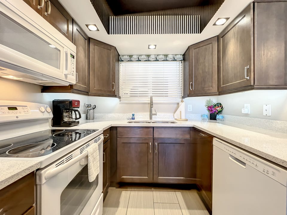 This efficient kitchen features sleek appliances, dark wood cabinetry, and a spacious countertop, perfect for cooking cozy meals in a stylish, well-lit space.