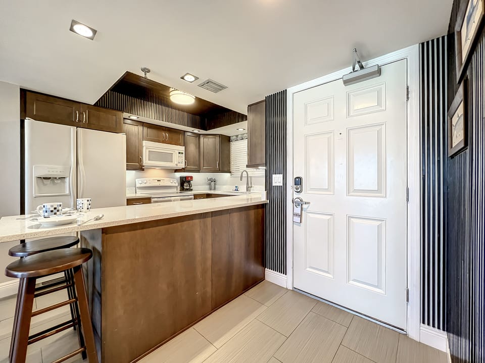 Step into this modern kitchen with stylish cabinetry, spacious countertops, and stainless appliances, perfect for whipping up meals after a day at the beach.