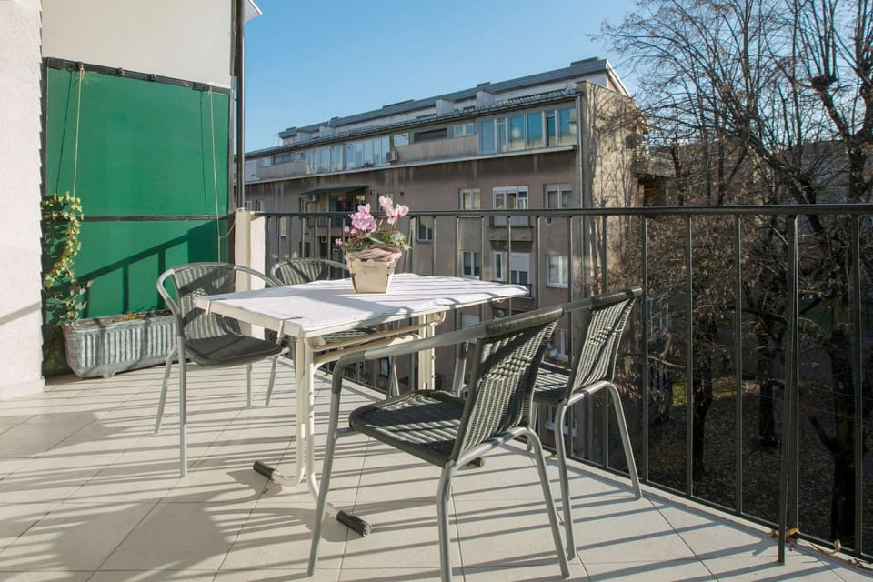 Sunny terrace with flowers and table with 4 chairs.