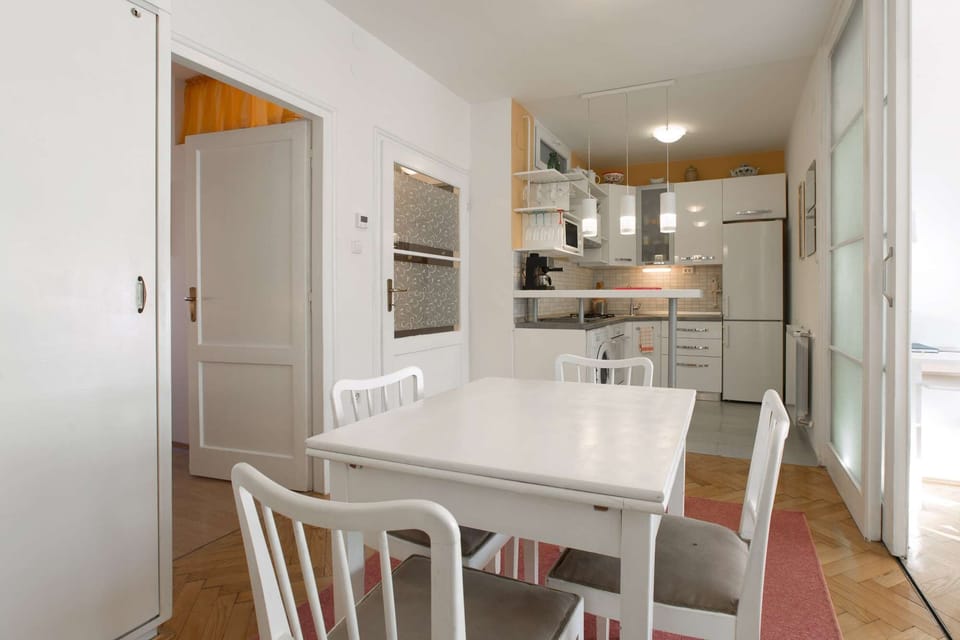 Dining area and fully equipped kitchen behind it. On the right is the entrance to the living room.