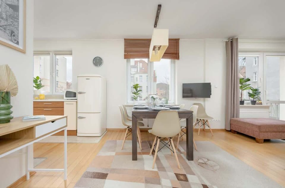 A bright dining area with a wooden table and contemporary chairs, complemented by large windows allowing plenty of natural light.

