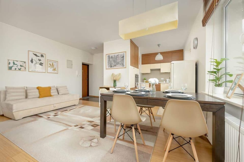 A beautiful dining setup with a wooden table, neutral-toned chairs, and a soft lighting fixture, perfect for hosting guests.


