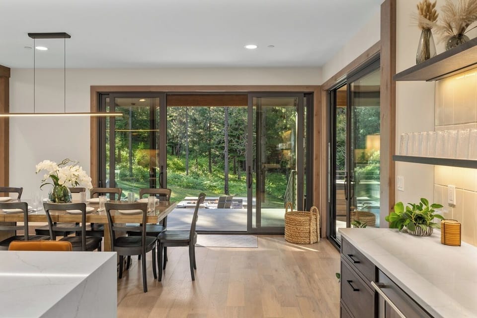 Wall-to-wall sliding glass doors create seamless indoor-outdoor flow from the dining area to the patio lounge.