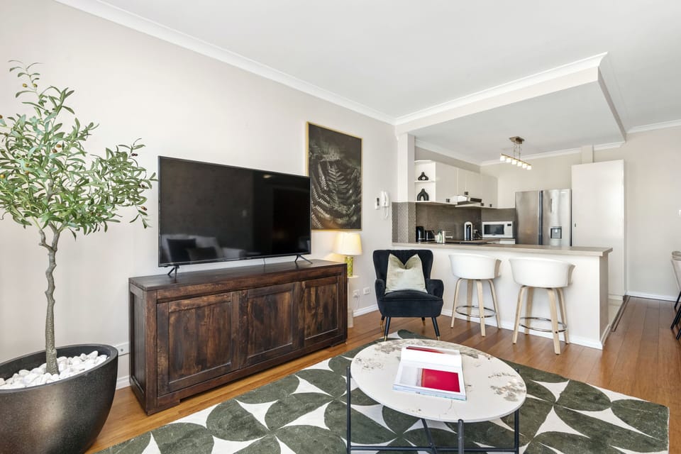 Entertain in style in this open-plan living area, featuring a spacious living room, a well-equipped kitchen with a breakfast bar, and a touch of greenery.