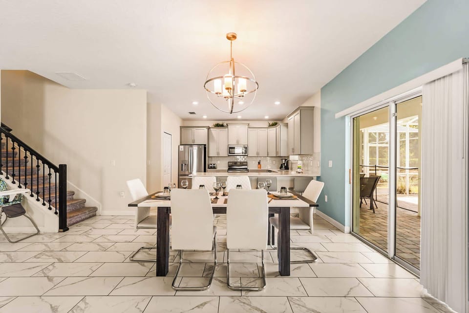 Elegant dining area with modern kitchen and patio access, perfect for family gatherings.