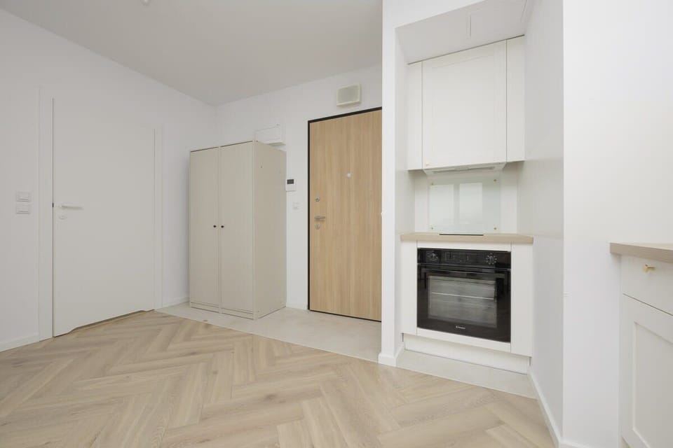 A bright hallway with built-in storage, a modern fireplace, and a minimalist aesthetic, leading to different rooms in the apartment.

