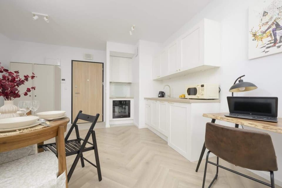 A spacious open-plan kitchen and dining area with white cabinetry, a built-in oven, and stylish wooden accents.

