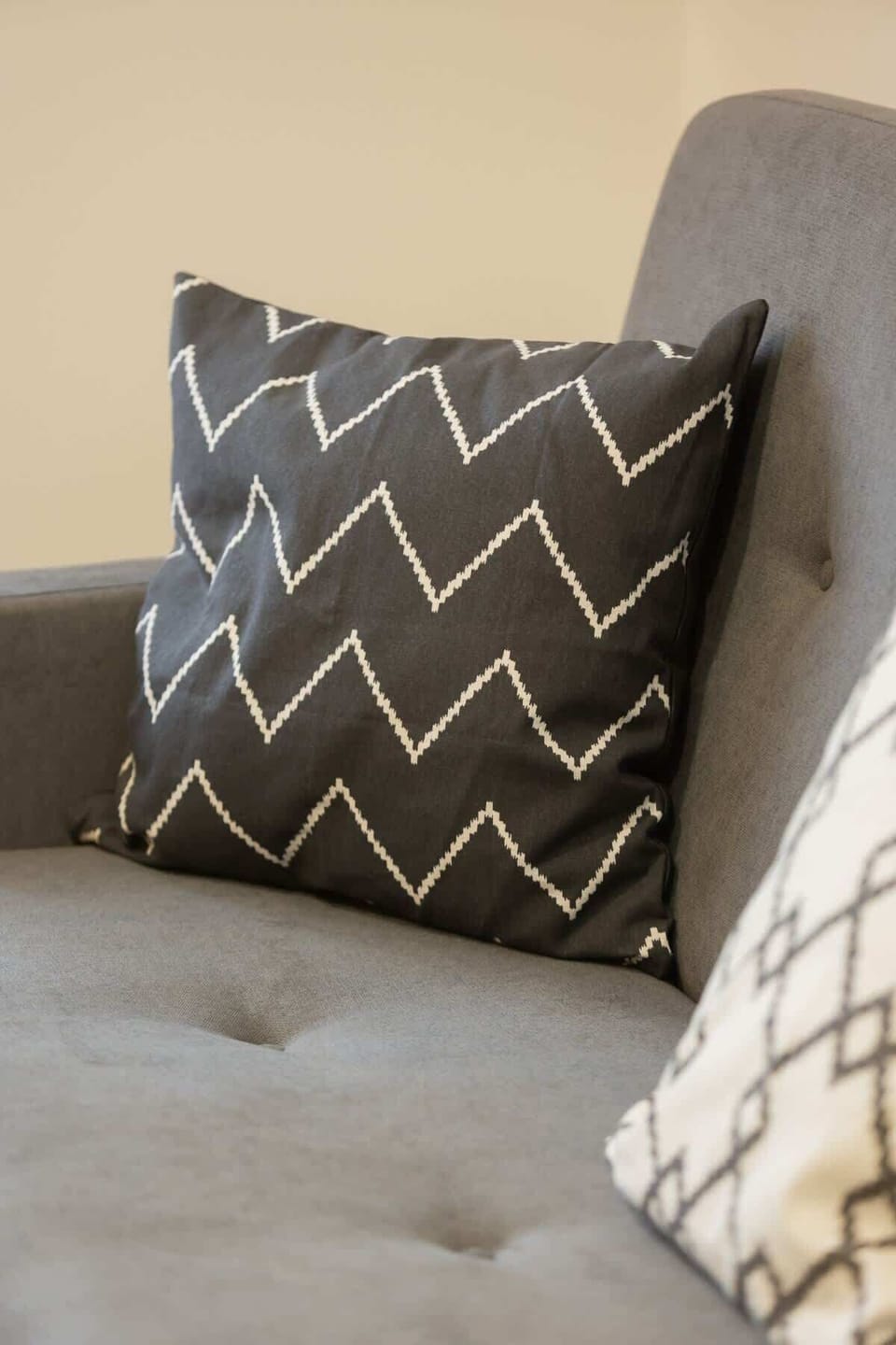 A close-up of a decorative pillow with a geometric pattern, adding texture and contrast to the neutral-toned sofa.


