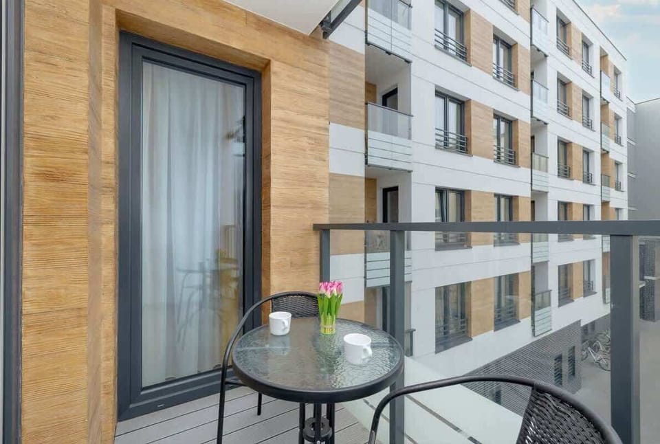 A view from the balcony, showcasing the modern architecture of the apartment complex with wooden and glass finishes.

