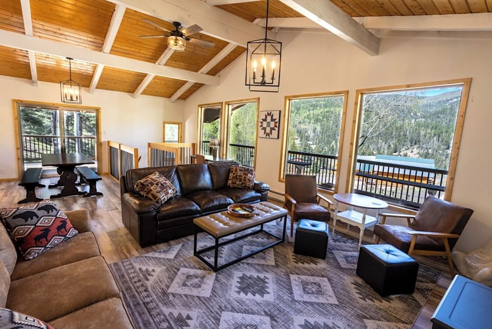 Your spacious mountain retreat features stunning lake and forest views from expansive windows, a cozy leather sectional, and warm wood-beamed ceilings that invite relaxation and connection with nature.