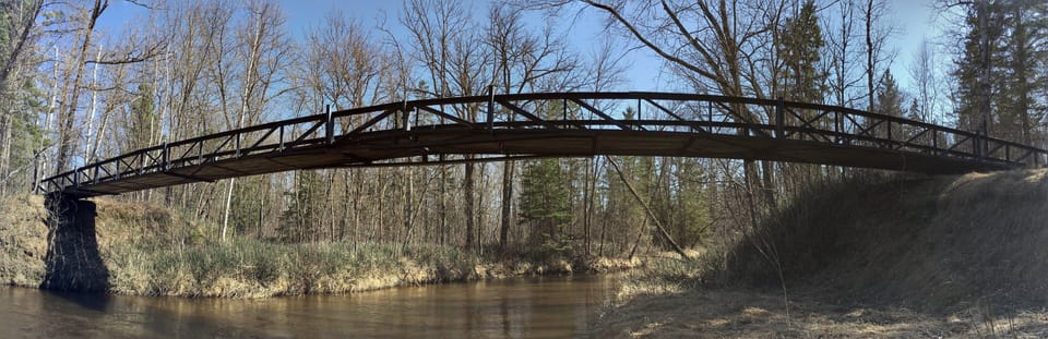 Cross our 110-ft walking bridge to the cement slab with basketball hoop beyond.