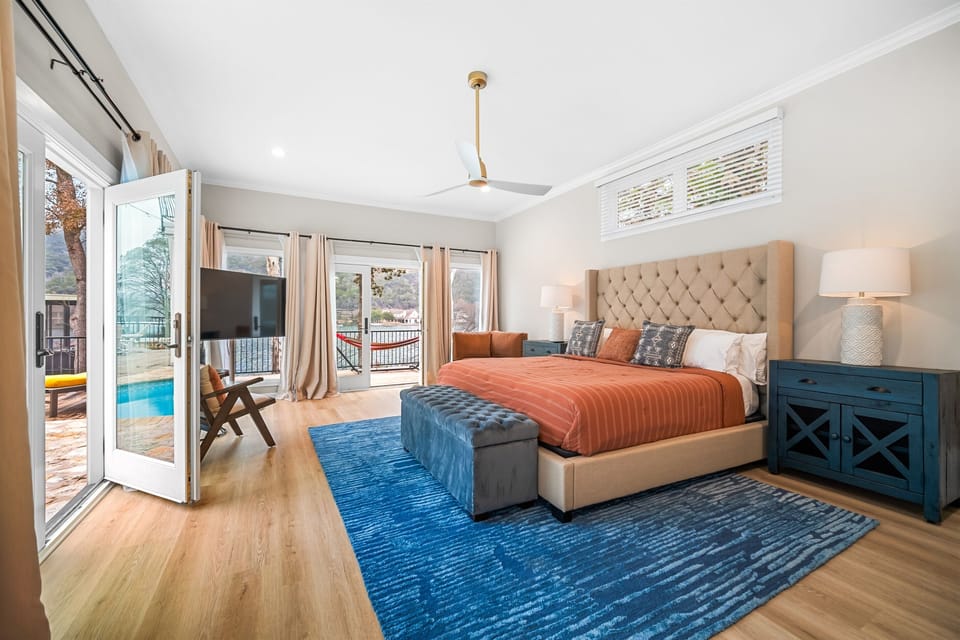 Bedroom #3: 1 King Bed, Ensuite Bathroom (lower level Primary) — With closet, dresser, 60" TV, and pool & lake view