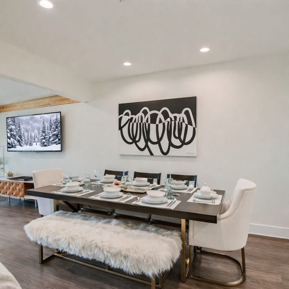 Stylish dining space with a modern table set for gatherings, plush seating, and chic décor. Enjoy an open, light-filled layout with contemporary art and a wall-mounted TV—perfect for shared meals and après-ski conversations.