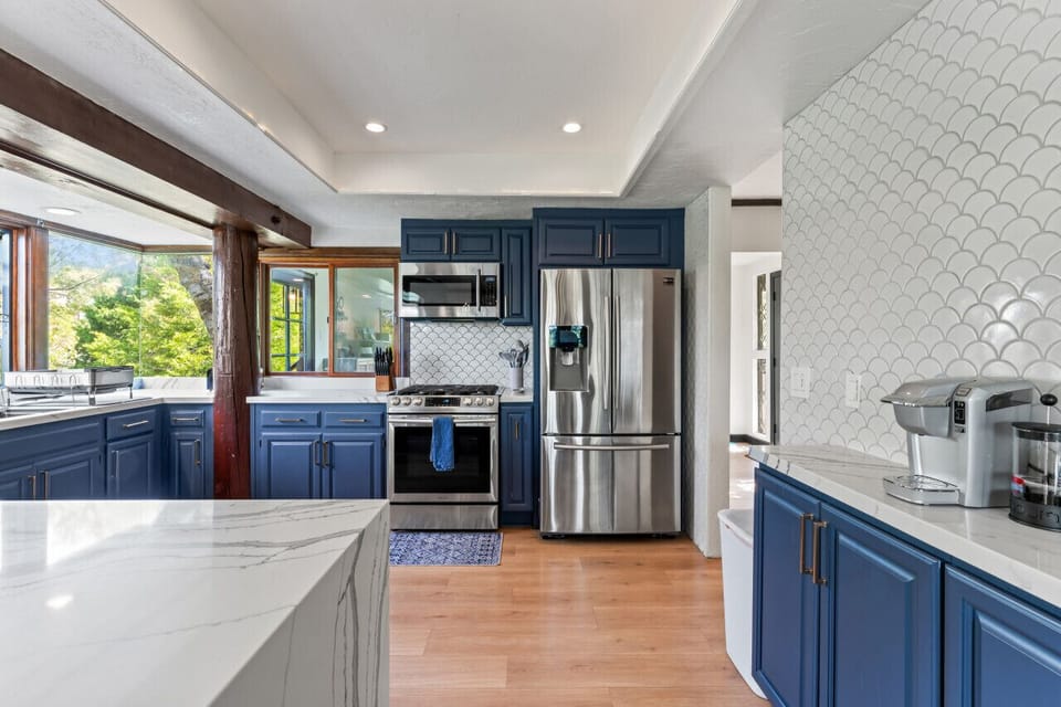 Bright kitchen w/ blue cabinetry, stainless steel appliances & a spacious island.