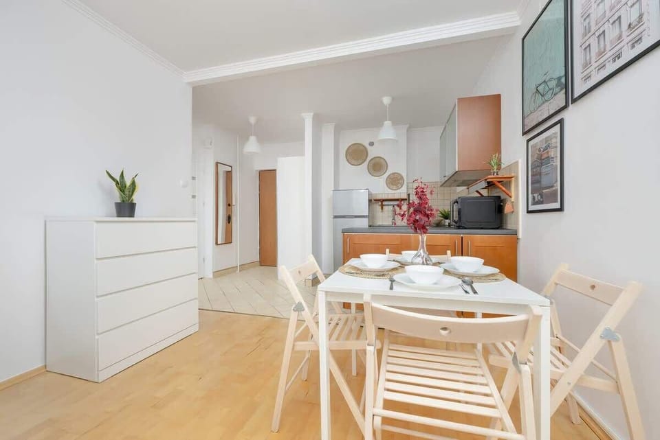 Another perspective of the dining and kitchen area, showcasing the wooden dining table, white chairs, and framed artwork adding character to the space.


