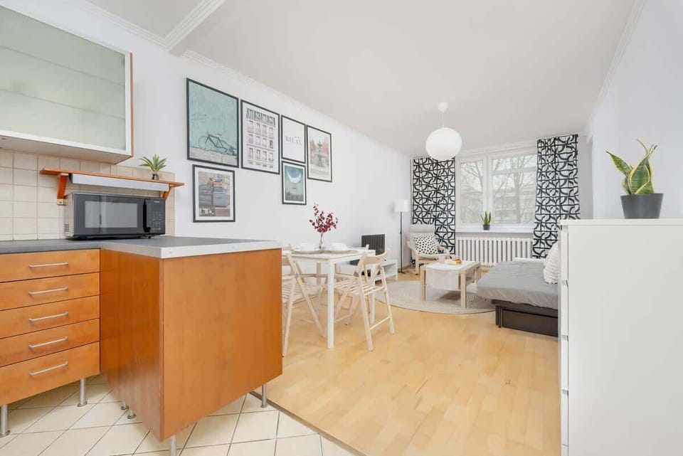 A stylish dining and kitchen area with a wooden sideboard, white dining table, and framed artwork adding a decorative touch to the space.

