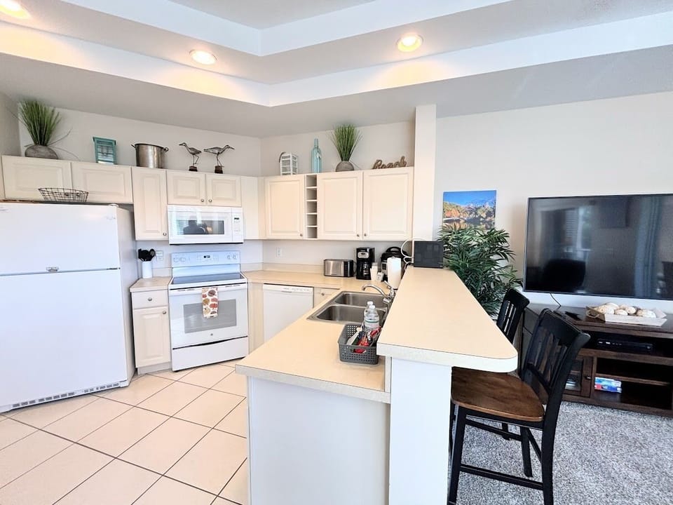 Fully equipped kitchen with full-size appliances, breakfast bar seating, and an open view into the living area.