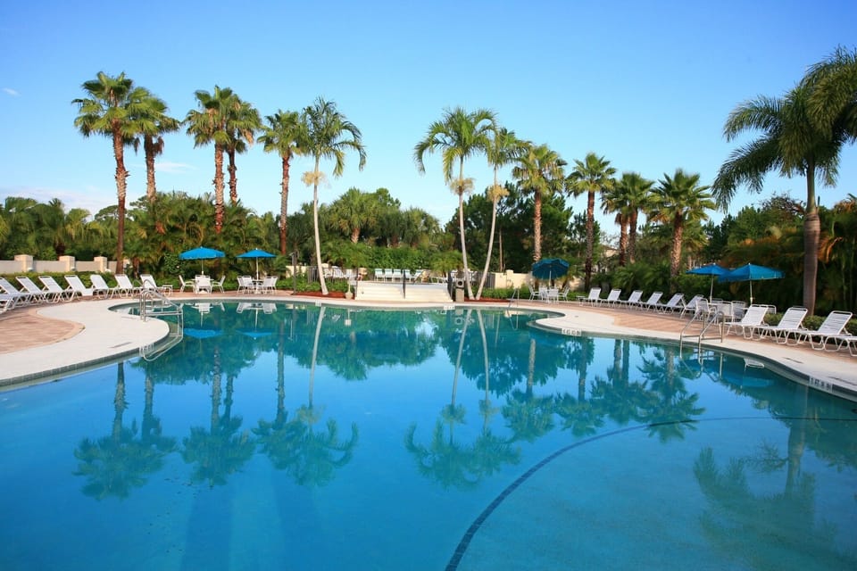 Resort-style community pool surrounded by tropical landscaping, palm trees, and lounge seating.