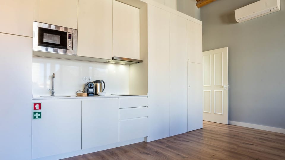 Unleash your inner chef in this sleek, well-equipped kitchenette, perfect for preparing delicious meals, while the nearby dining area offers a cozy spot to enjoy your culinary creations. The air conditioning ensures comfort during your cooking adventures.
