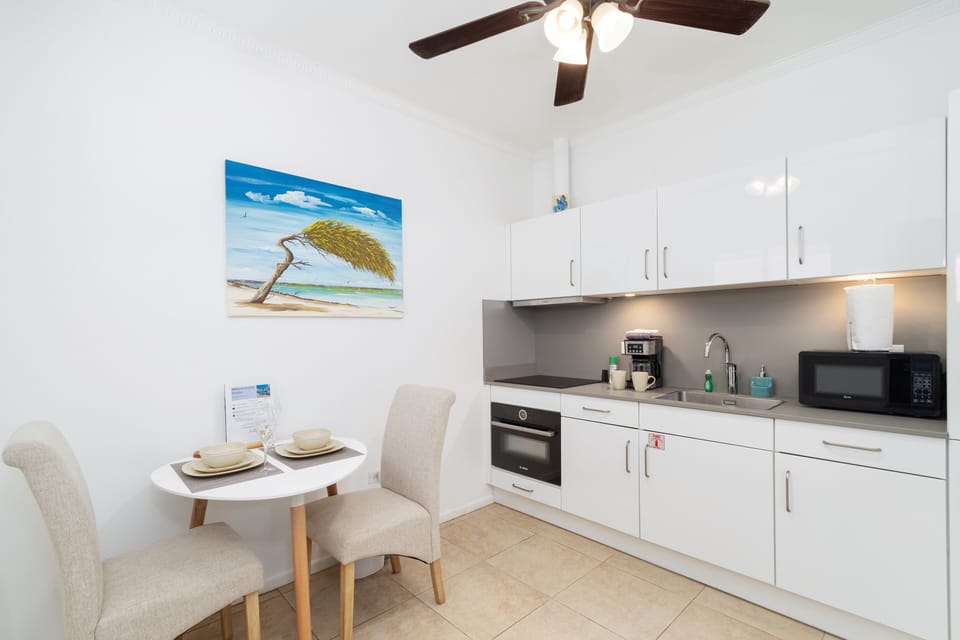 Dining and Kitchen Area of the Apartment in Noord Aruba - 3 Persons Dining - Thoughtful lighting fixtures creating an intimate and inviting atmosphere - Functional and aesthetically pleasing area