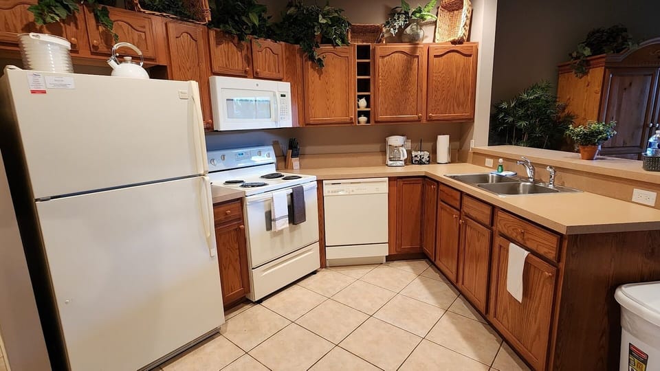 Fully equipped kitchen with full-size appliances, cabinet storage, tile flooring, and convenient counter space.