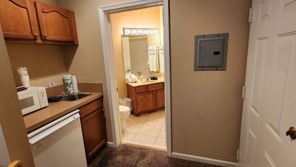 Convenient kitchenette area with microwave, mini fridge, sink, and easy access to the bathroom.
