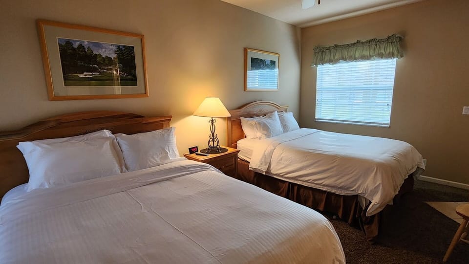 Bright bedroom featuring two comfortable beds, bedside lighting, and a cozy, relaxing setup.