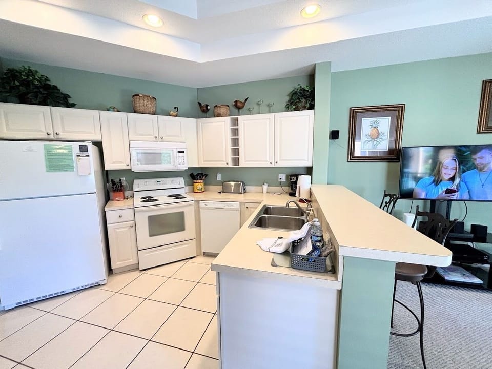 Fully equipped kitchen with full-size appliances, breakfast bar seating, and an open view into the living area.