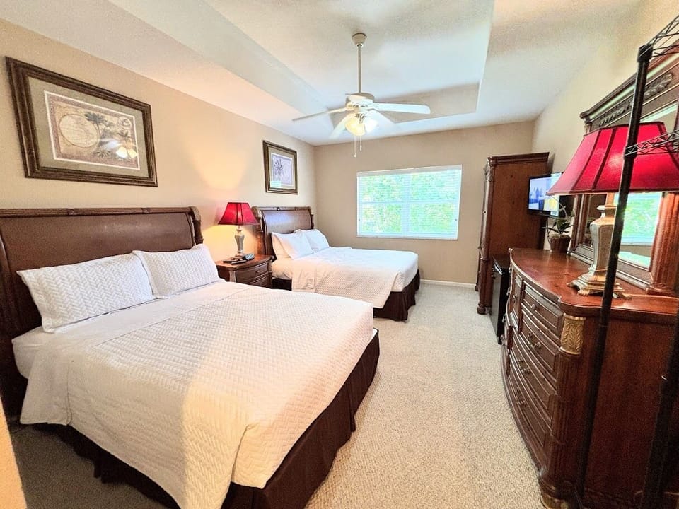 Comfortable bedroom featuring two beds, dresser storage, ceiling fan, TV, and plenty of natural light.