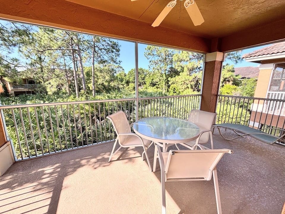 Private screened balcony with outdoor seating and peaceful views of the surrounding greenery.