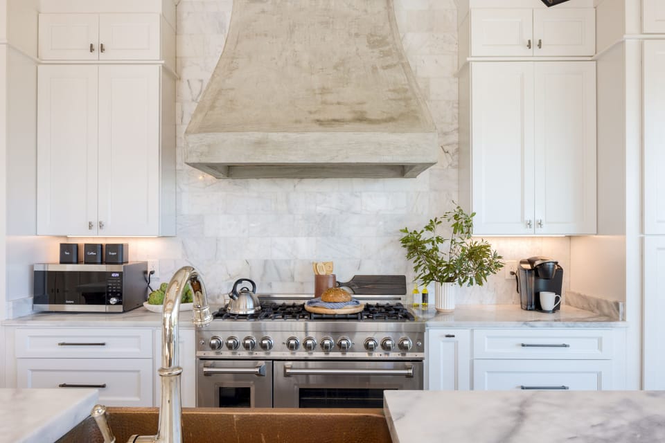 Chef's kitchen features top-of-the-line appliances and a marble backsplash.
