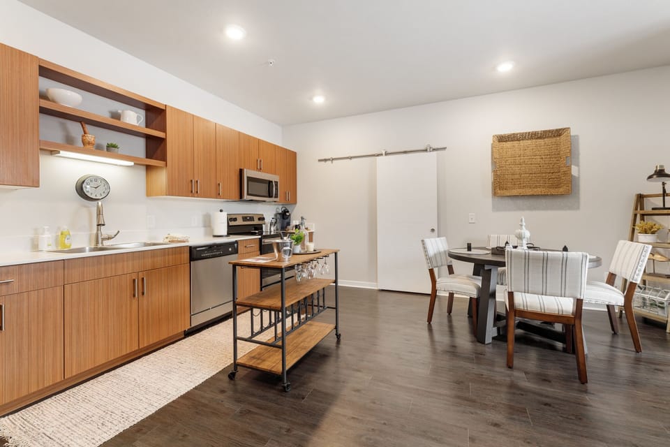 Open kitchen & dining area w/ warm wood cabinets & sleek finishes