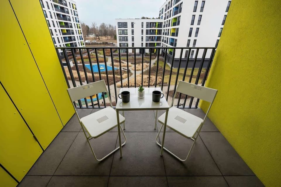 A second perspective of the yellow-walled balcony, offering a more immersive view of the comfortable outdoor seating area and the landscaped courtyard below.







