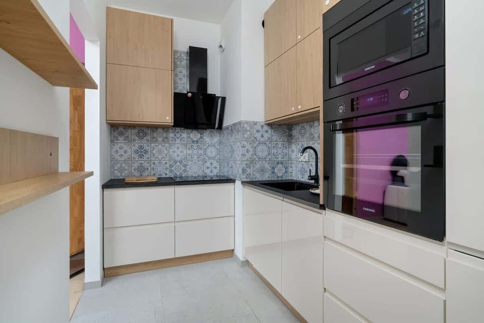 A compact yet modern kitchen with white cabinetry, a built-in oven, and sleek granite countertops, offering a functional cooking space.

