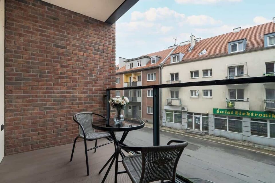 A private balcony with a seating area, offering a relaxing outdoor space with a view of the surrounding residential buildings.

