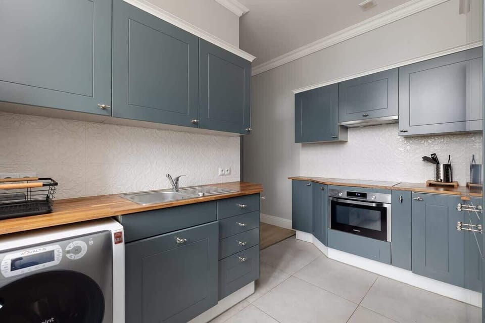A fully equipped kitchen with navy-blue cabinetry, a washing machine, a microwave, and ample counter space for cooking and dining convenience.

