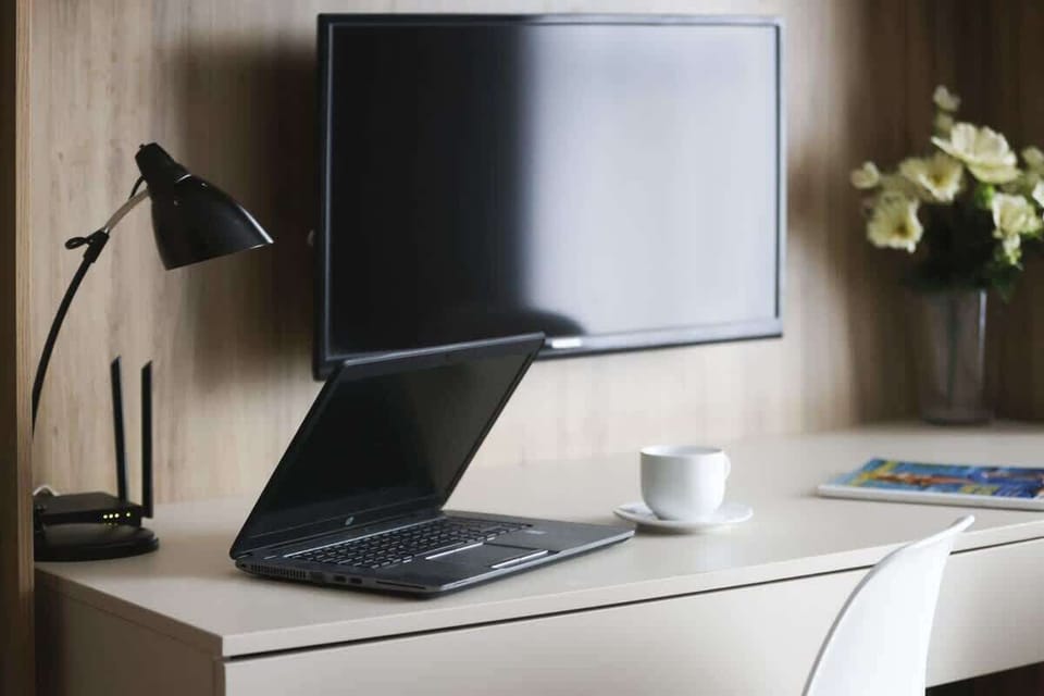 A well-organized desk area with a modern black lamp, a computer monitor, and a fresh green plant for a productive work environment.

