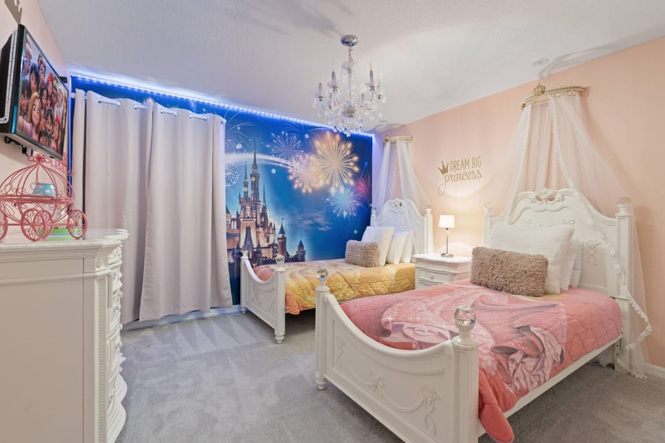 This cheerful bedroom, with its colorful decor and cozy twin beds, invites relaxation after a day of fun. Charming white furniture, soft bedding, and a whimsical mural enhance the playful atmosphere for a delightful stay.