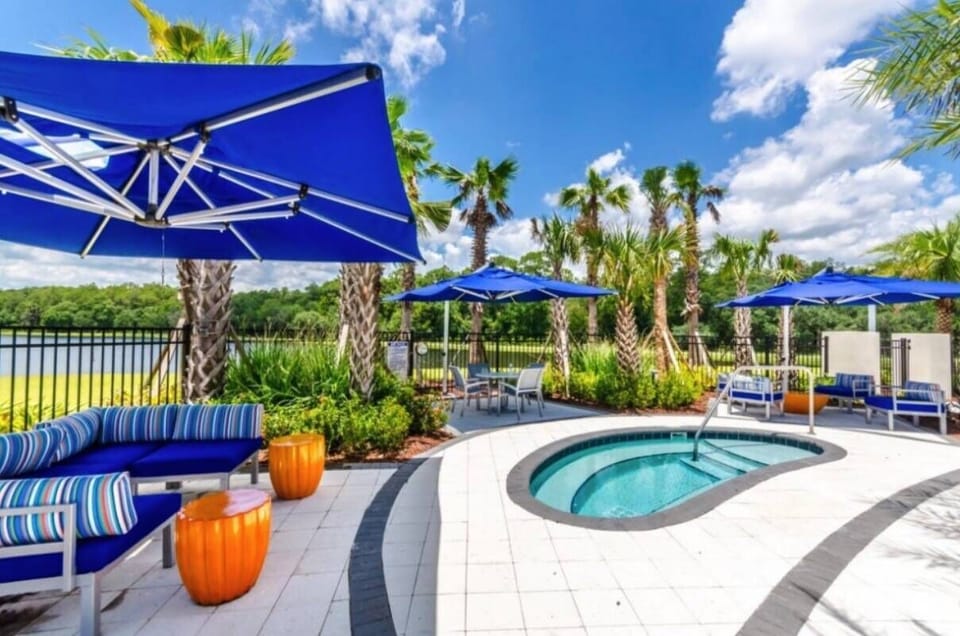 Enjoy your private paradise with a pool nestled among palm trees and colorful loungers. Bright blue umbrellas offer shade for your relaxing afternoons, while the chic seating area beckons you to unwind and soak in the tranquility.