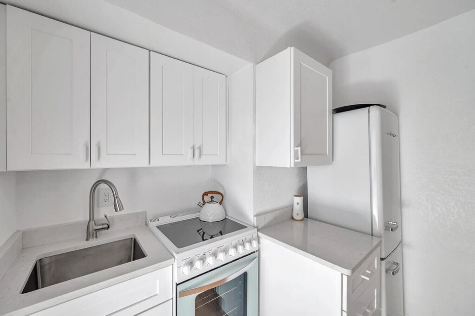 Bright white kitchen w/ clean lines, ample cabinets, & an easy, uncluttered layout for simple meals.