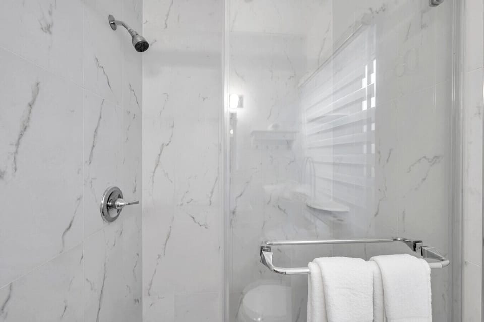 Sleek bathroom w/ tiled walls & a glass-enclosed tub-shower combo for a clean, refreshing feel.